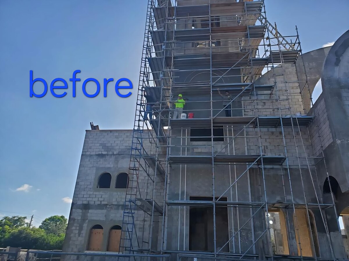 Workers on scaffolding applying stucco base coat to church tower and walls with visible steel arch framing in Brandon, FL — H Calix Stucco Design & Paint LLC.