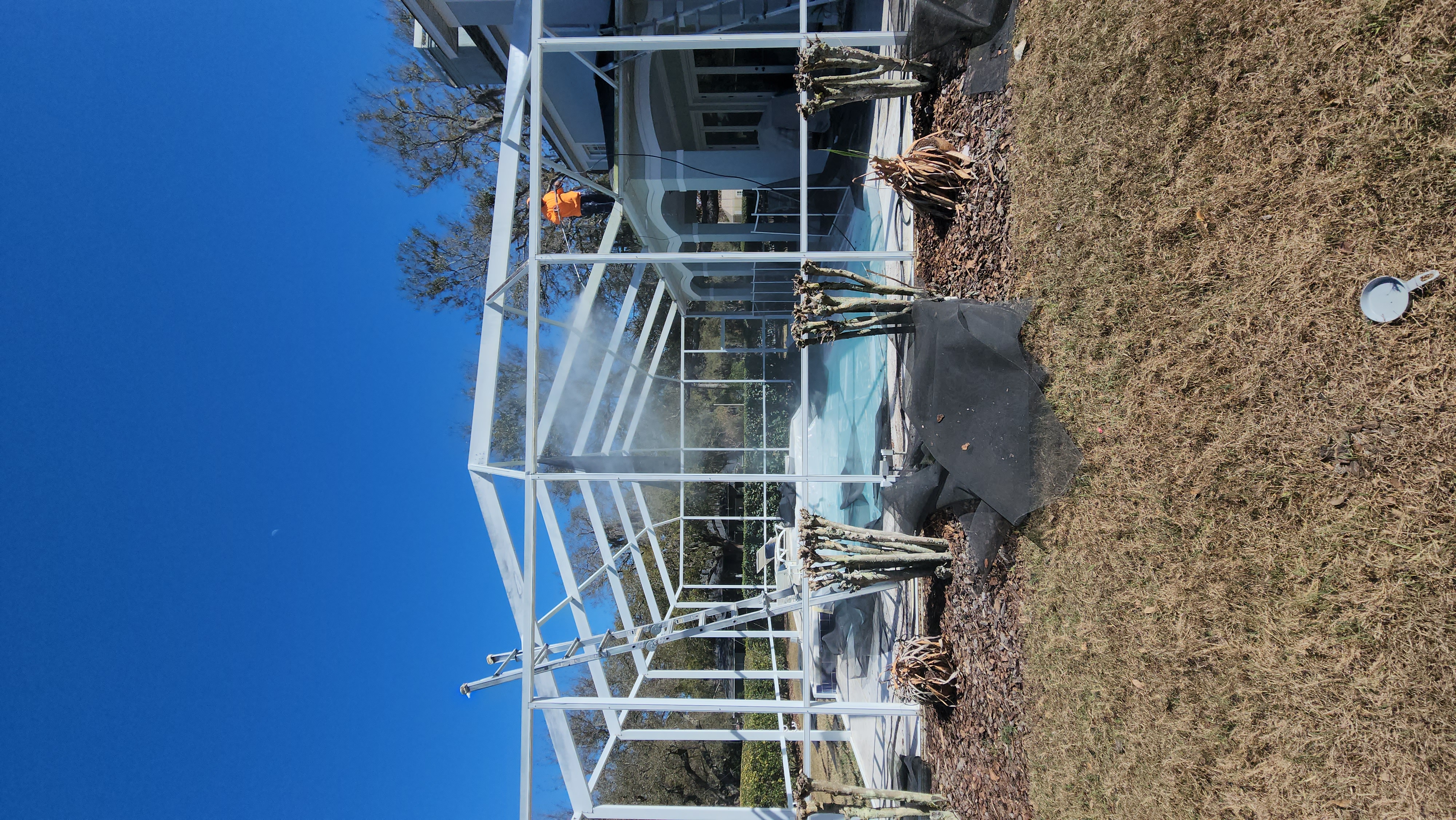 Professional pool cage painting and screen enclosure restoration in Lutz FL by H Calix Stucco Design & Paint LLC — pool and patio prepared and masked before repainting