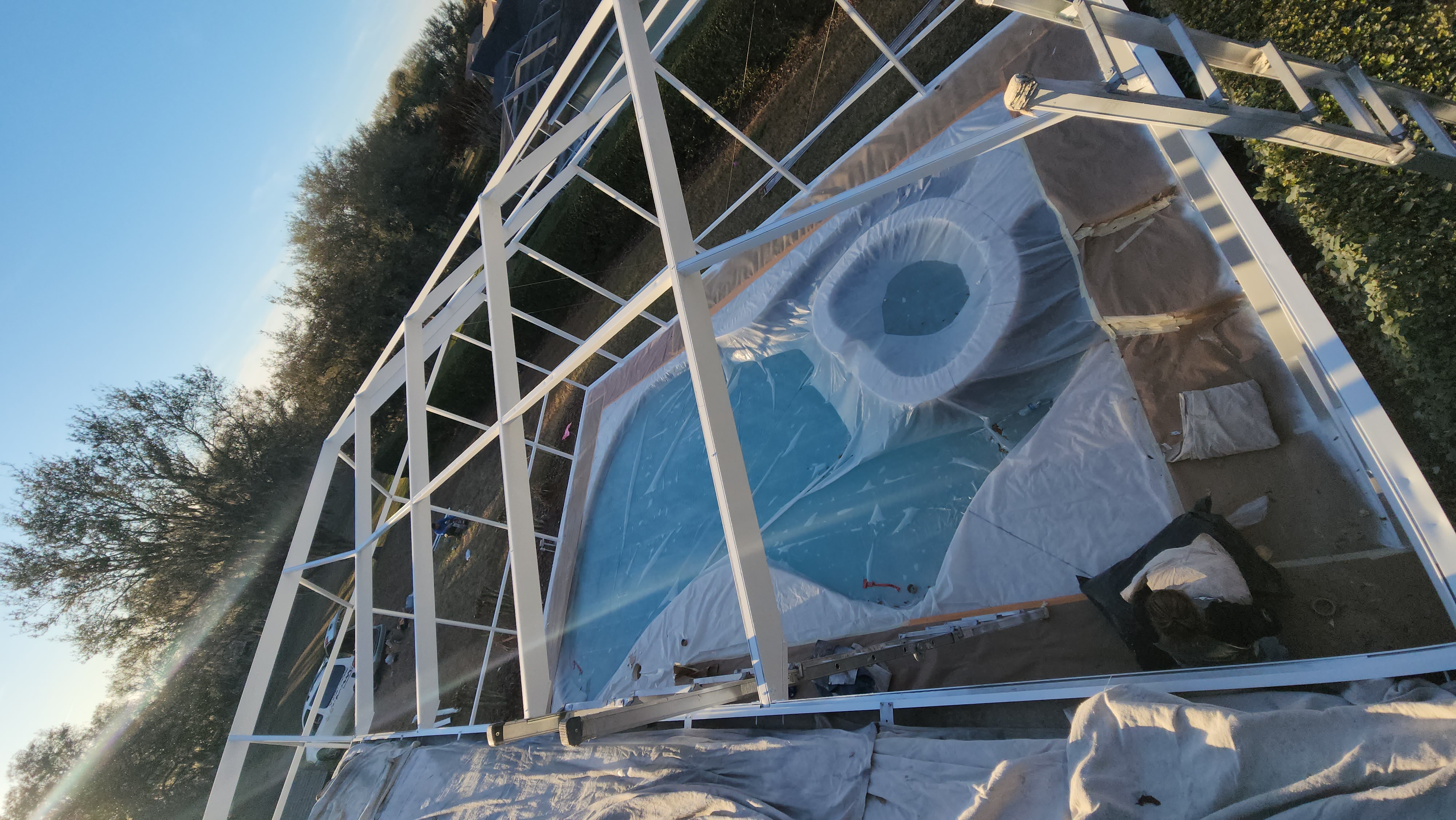 Professional pool cage painting and screen enclosure restoration in Lutz FL by H Calix Stucco Design & Paint LLC — protective roof and enclosure masking during coating application