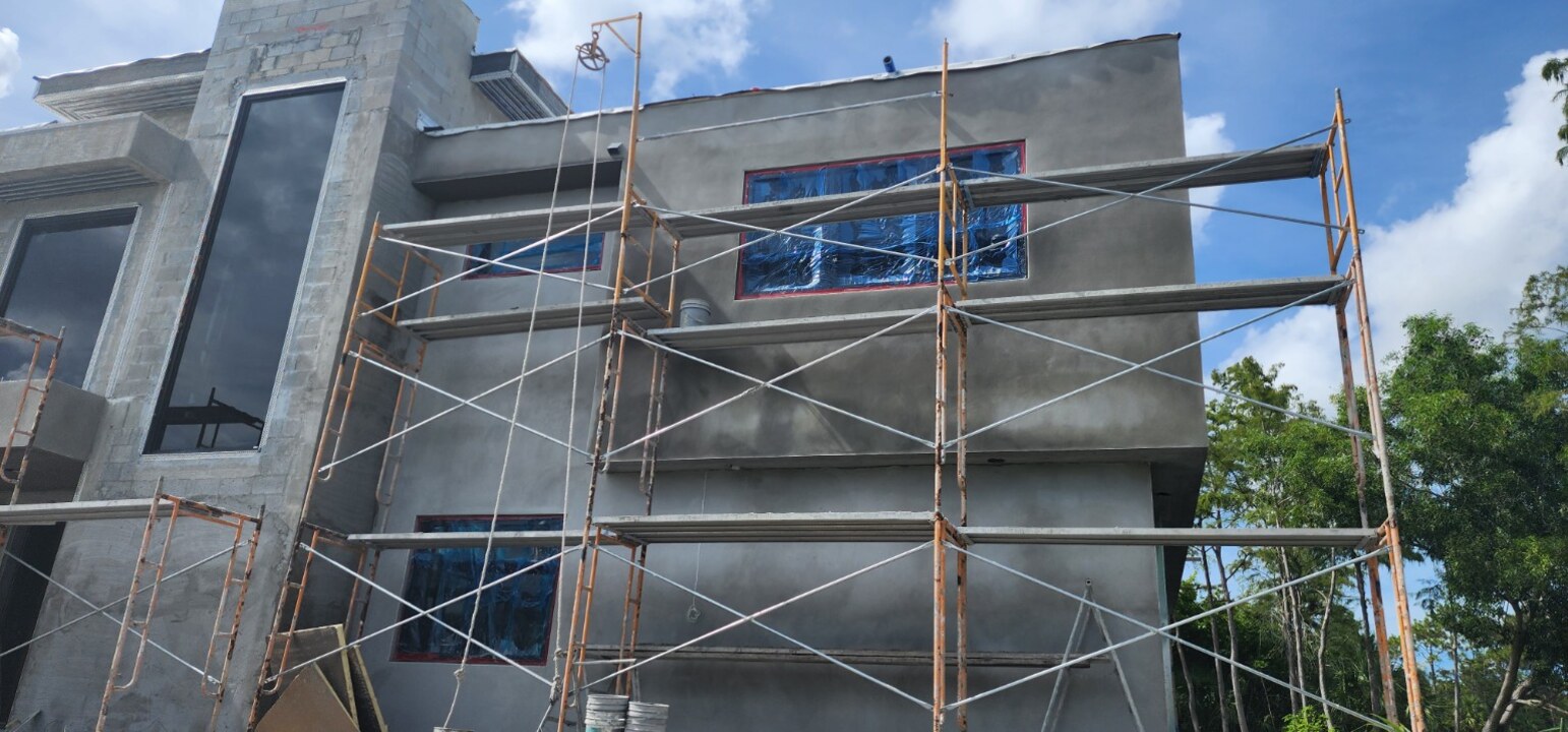 Smooth gray base-coat stucco applied on modern residential exterior with scaffolding in St. Petersburg, FL — H Calix Stucco Design & Paint LLC.
